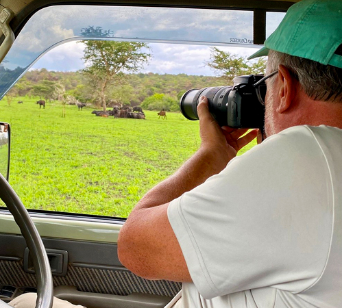 A Solo Traveler having a photo moment in his rented car in Queen Elizabeth National Park